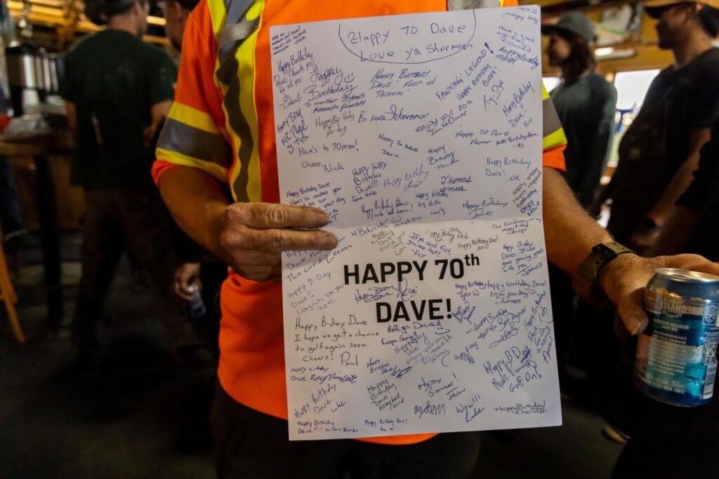 Dave holding up a card filled with staff signatures.