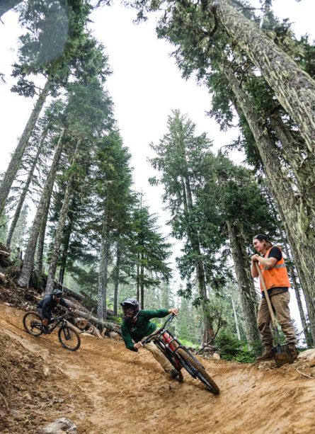 A mountain biker riding a bermed trail in the summer bike park
